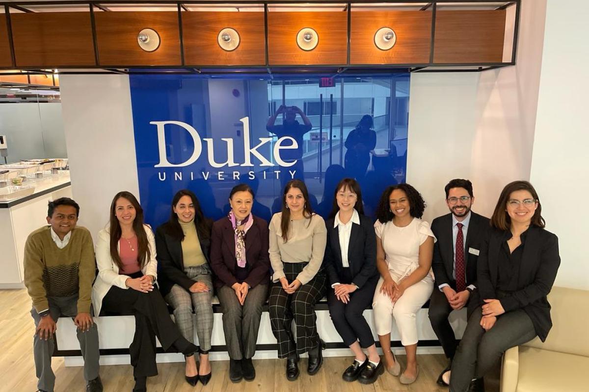 Nine people sitting in front of a Duke University sign
